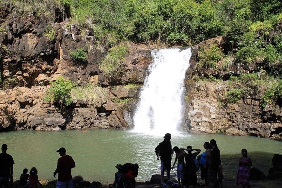 A group of people standing around in front of a waterfall.