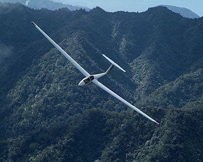 A small plane flying over the top of a mountain.