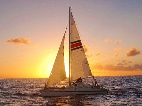 A sail boat sailing in the ocean at sunset.