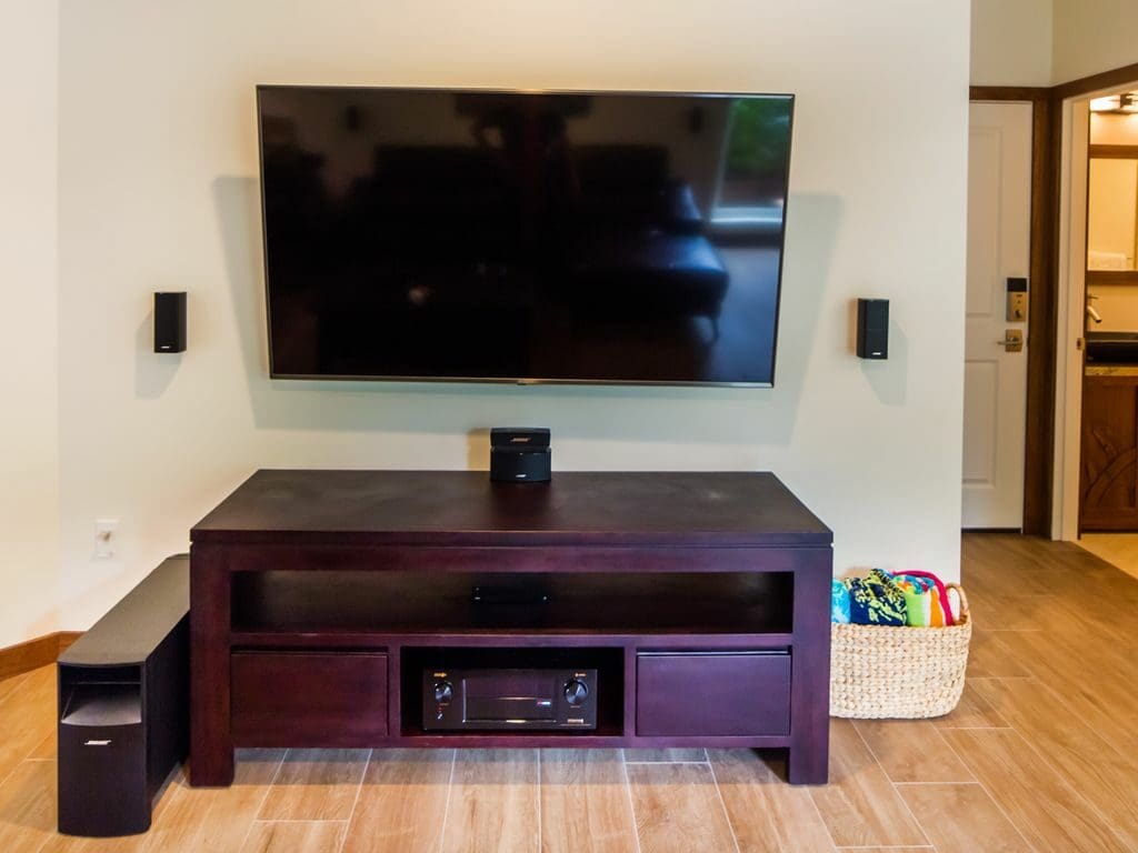 A flat screen tv mounted on the wall above a wooden table.