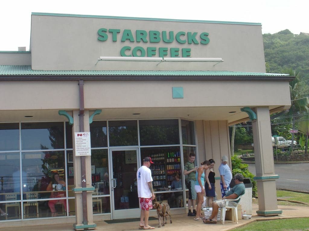 A starbucks coffee store with people and dogs outside.
